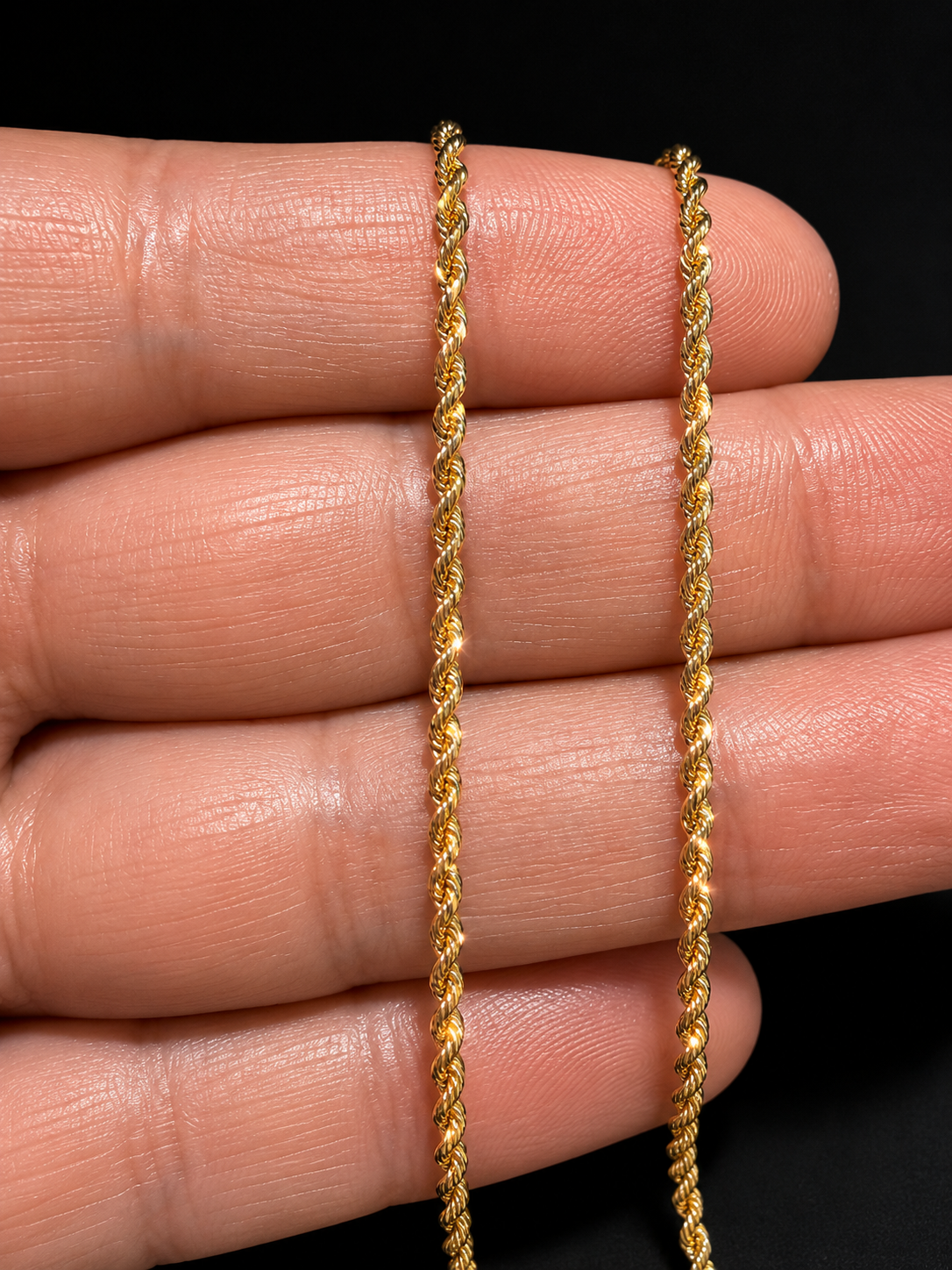 Close-up of 14K gold rope chain texture on black background